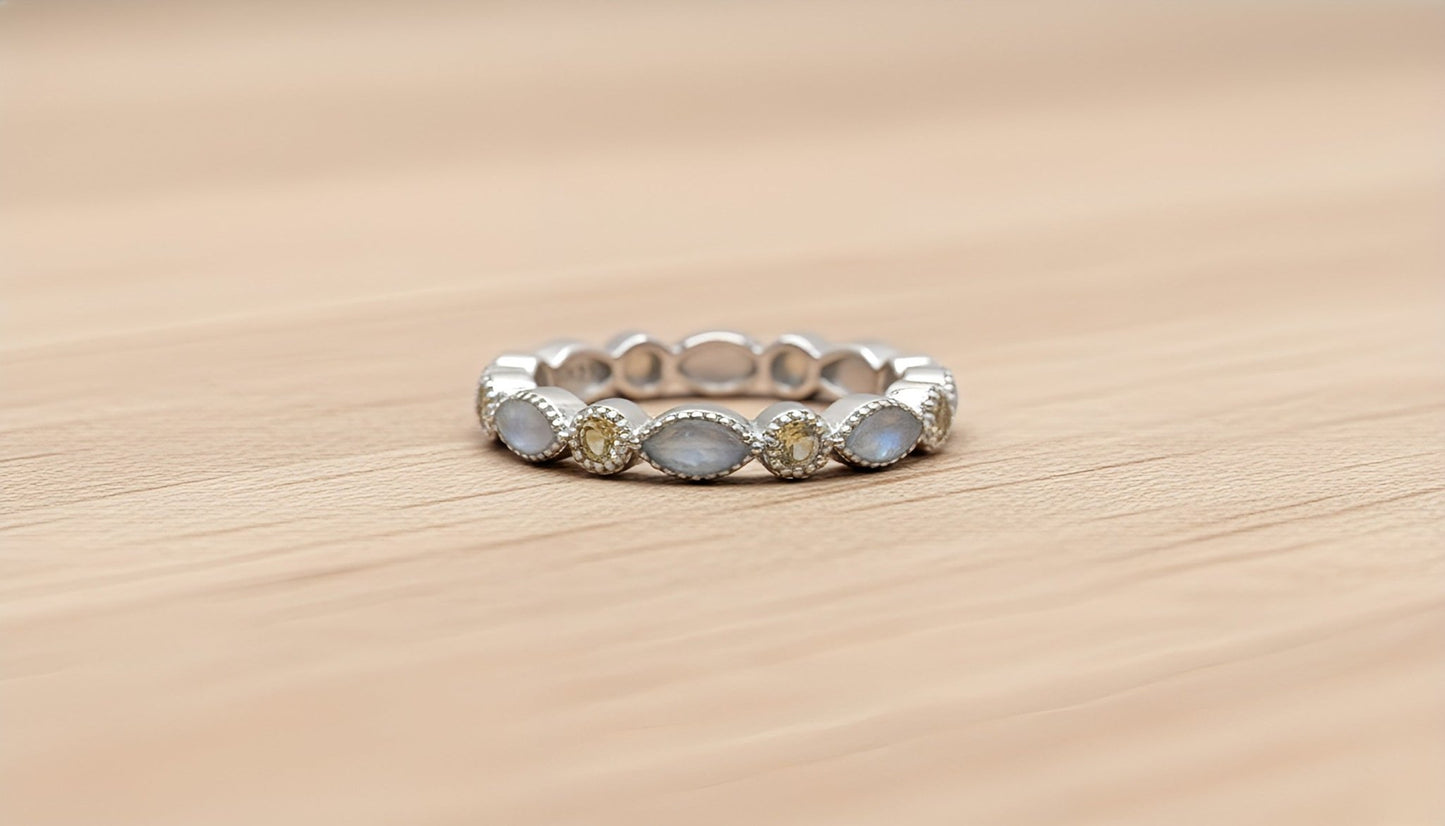 Silver ring with embedded white and yellow stones on a wooden surface