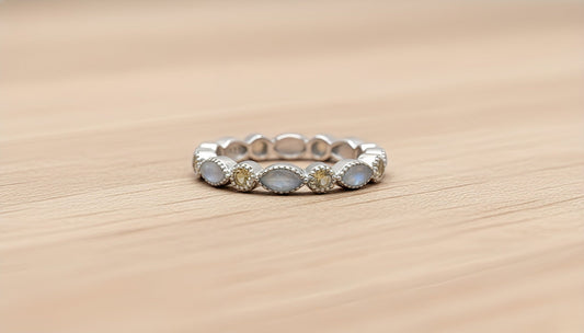 Silver ring with embedded white and yellow stones on a wooden surface