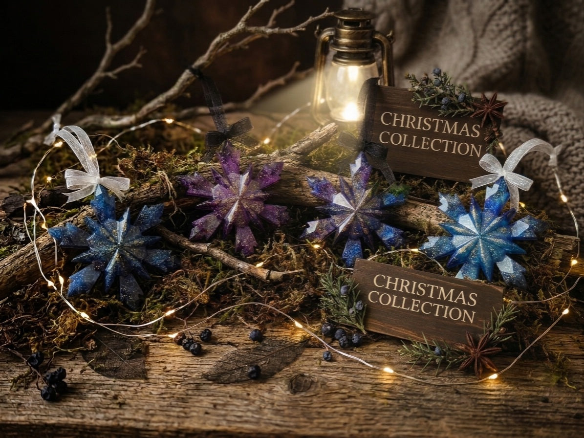 Galaxy resin Christmas ornaments in blue and purple displayed on a rustic wooden surface with fairy lights, moss, and a vintage lantern