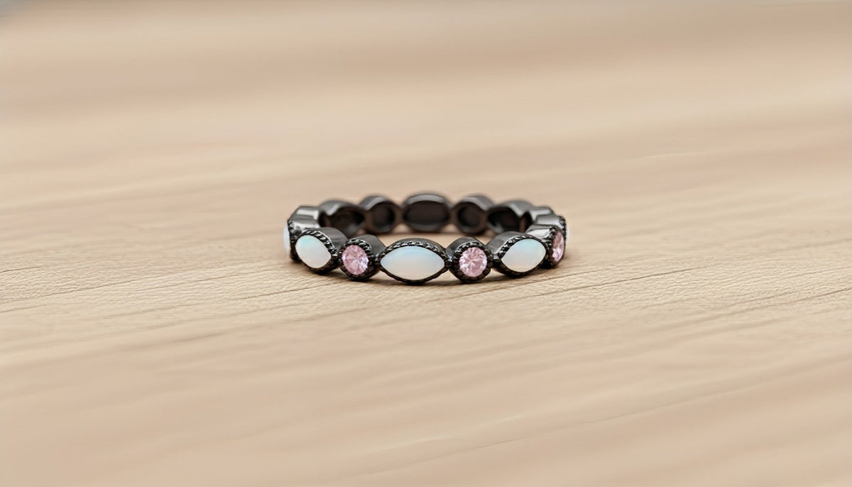 Black ring with pink and white stones on a wooden surface