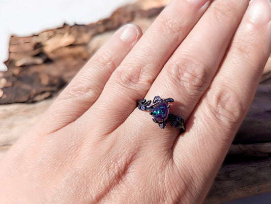 Lilith's Embrace ring. Sterling silver, plated with black rhodium with amethyst accent stones. Bloodstone center stone is purple with purple crushed opal. A woman is wearing the ring-milky way spirit & soul Keepsakes.