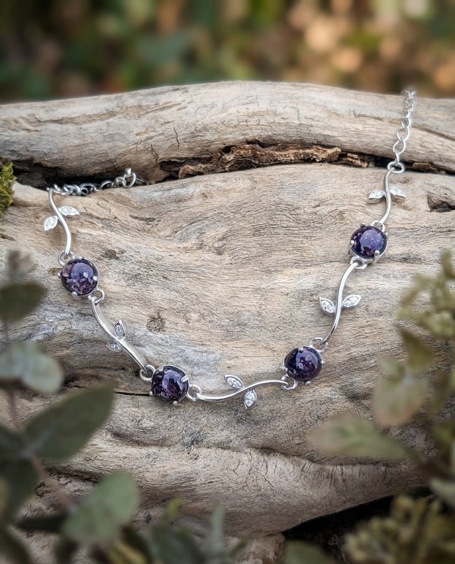 Silver ash necklace with purple stones on a wooden log