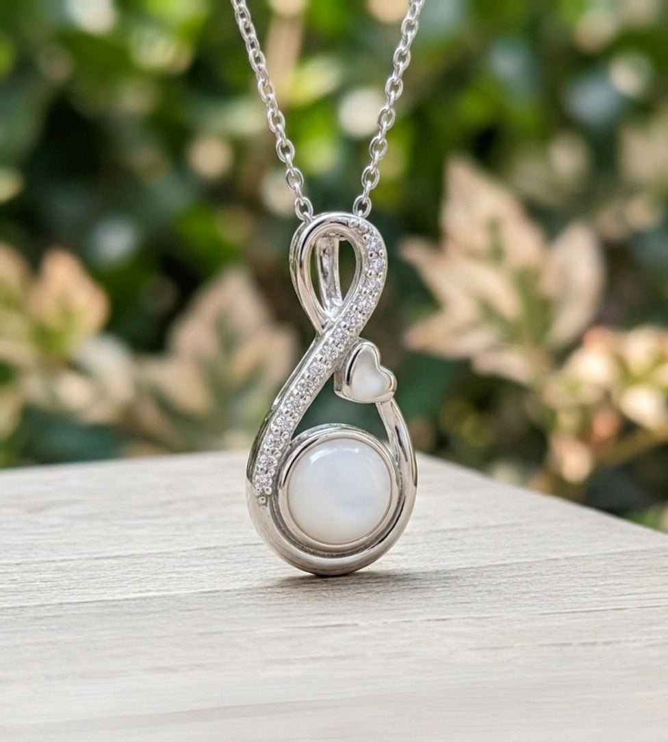 Silver necklace with a pendant featuring a milk pearl on a wooden surface with a blurred green background
