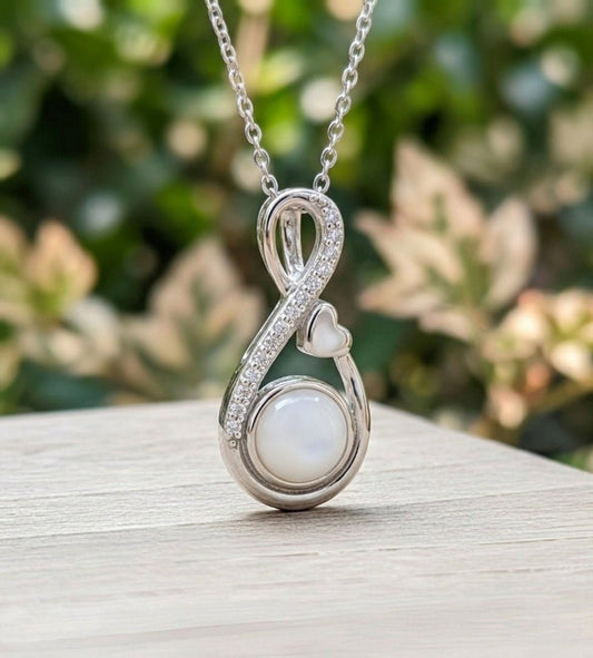 Silver necklace with a pendant featuring a milk pearl on a wooden surface with a blurred green background