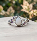 Silver ring with a teardrop-shaped gemstone on a wooden surface with a blurred natural background.
tear-of-eden-milky-way-spirit-soul-keepsakes