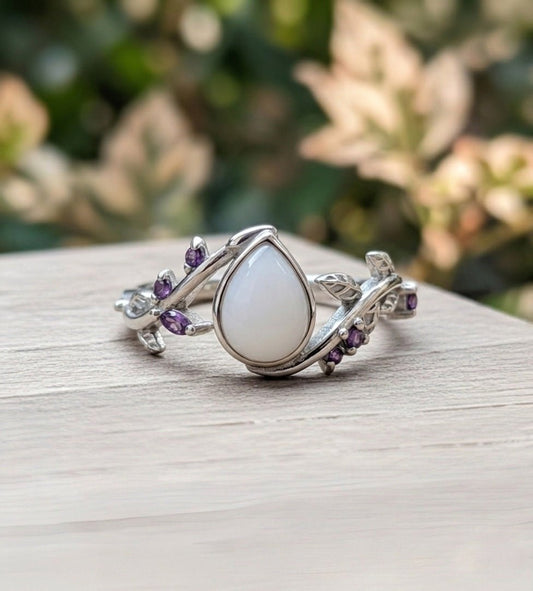 Silver ring with a teardrop-shaped gemstone on a wooden surface with a blurred natural background.
tear-of-eden-milky-way-spirit-soul-keepsakes